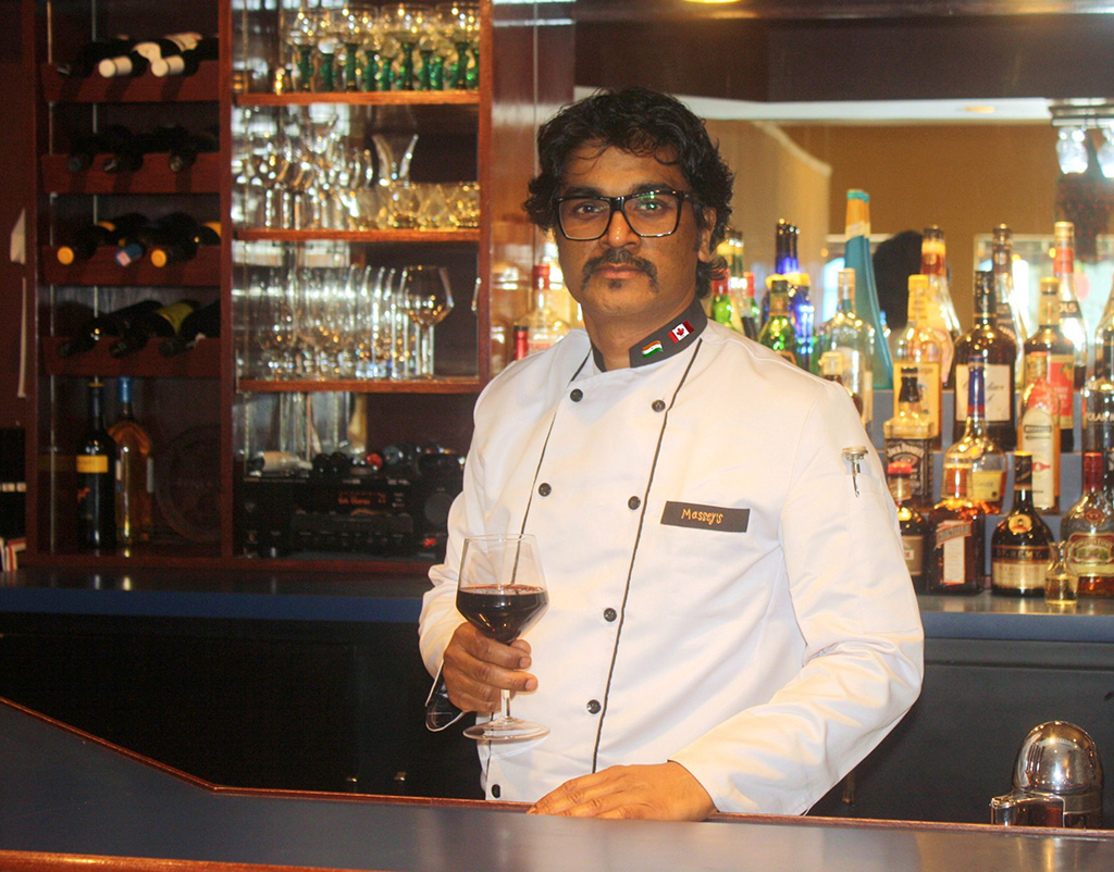 Chef Paston holding wine at his Indian Restaurant